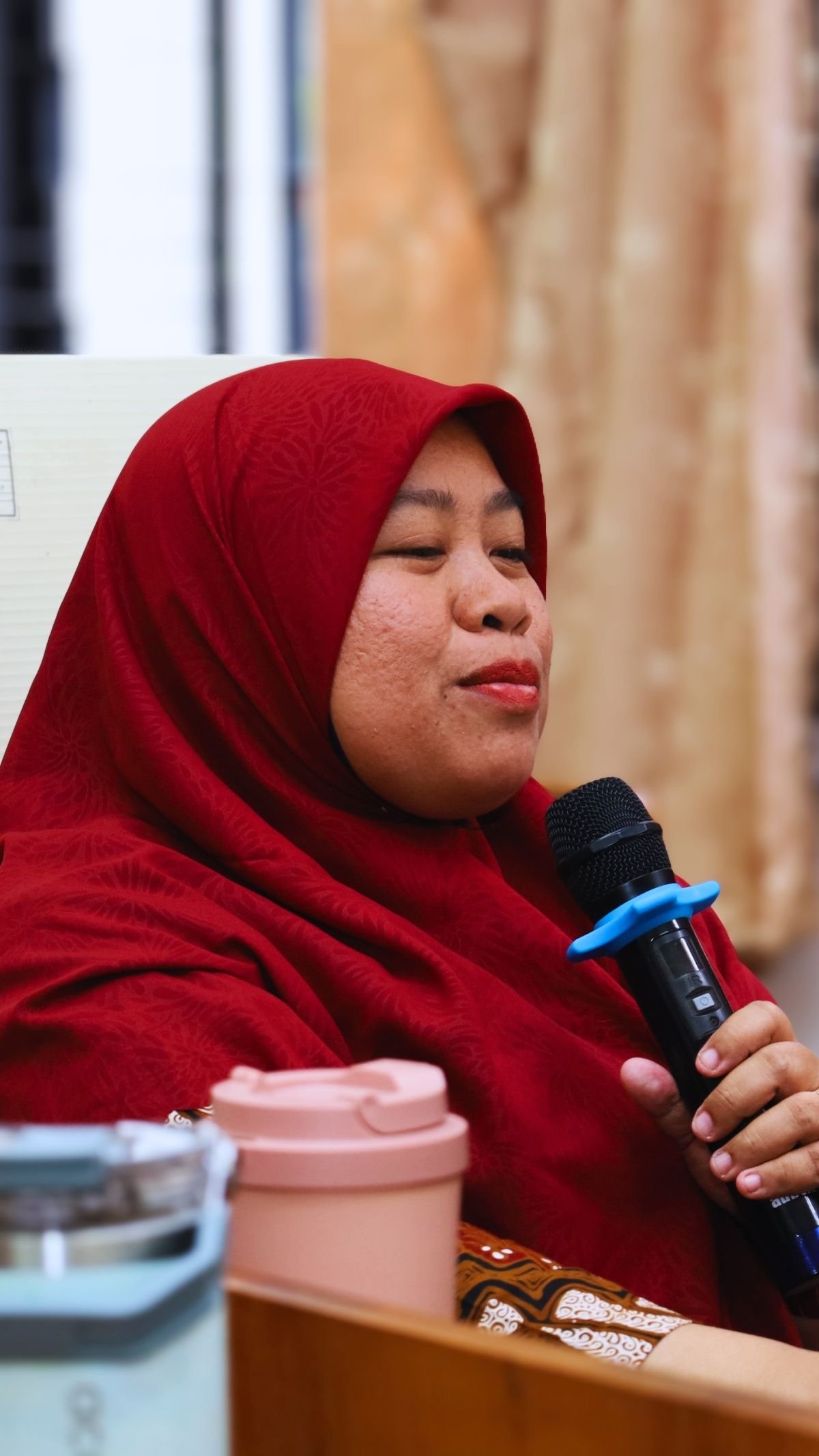 Peserta perempuan berbicara menggunakan mikrofon dalam sesi diskusi.